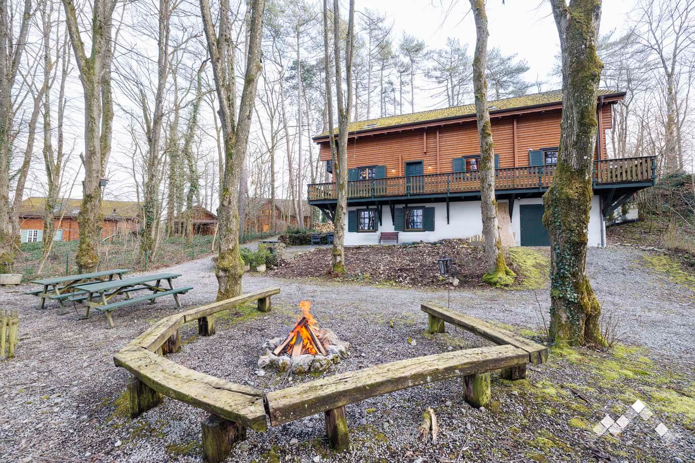 Espace feu de camp extérieur avec brasero et bancs en bois devant le chalet à Bomal-sur-Ourthe, Durbuy.